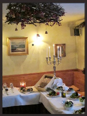Festlich gedeckter Tisch mit Kerzenleuchter unter einer Weinranke