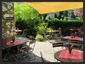 Biergarten mit Tischen unter einer großen Sonnenschutzplane